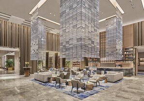 A spacious lobby with high ceilings, a central seating area, and a bar. - Hilton Yancheng (Yancheng)