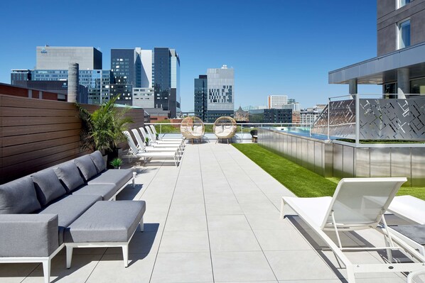 A rooftop terrace with a modern outdoor seating area, a pool, and a city skyline view. - Homewood Suites by Hilton Montreal Downtown, QC (Montreal)