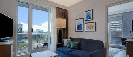 Ein modernes Wohnzimmer mit großem Fenster, Flachbildfernseher, Sofa und Couchtisch.