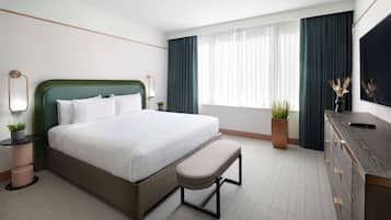 A hotel room with a bed, a bench, a dresser, and a TV.