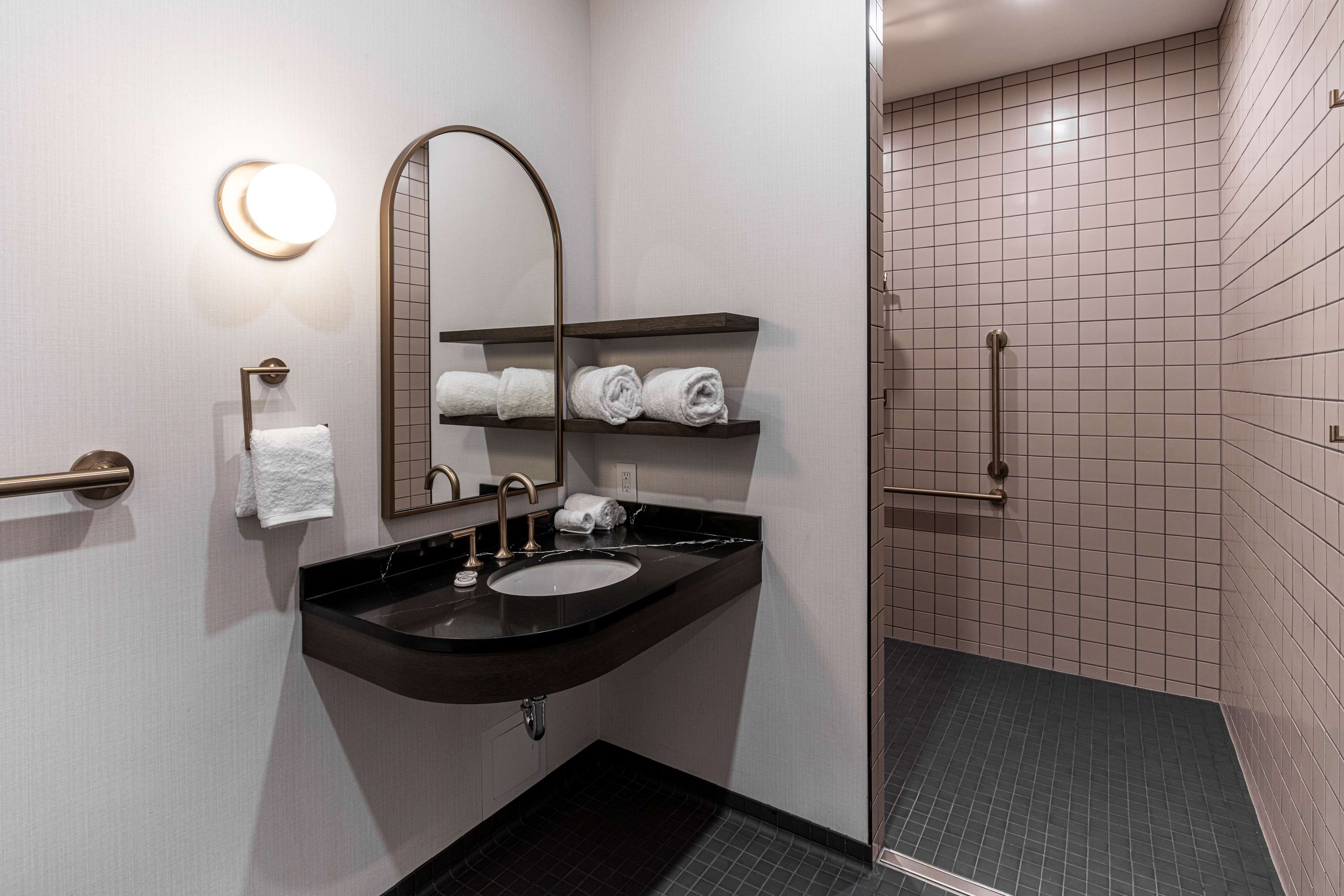 A modern bathroom with a sink, mirror, towel rack, and a shower area.
