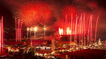 A nighttime view of a city with fireworks, a large dome structure, and a Ferris wheel.