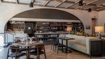 A modern restaurant with a curved ceiling, wooden furniture, and a bar area.