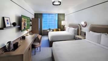 Habitación de hotel con dos camas, un escritorio con cafetera, una silla, televisor y ventana con cortinas.