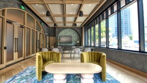 A modern hotel lobby with a large window, a round table, and two green armchairs. - The Westley Hotel - Tapestry Collection by Hilton (Calgary)