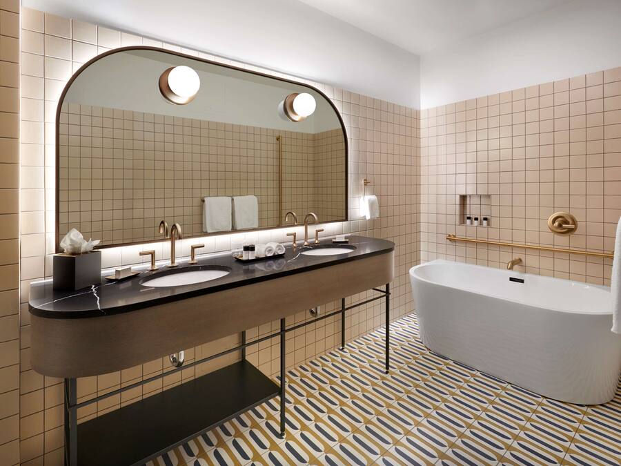 Ein modernes Badezimmer mit zwei Waschbecken, einem großen Spiegel und einer freistehenden Badewanne.