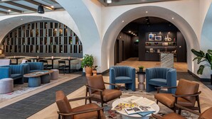 A modern lobby with seating areas, a reception desk, and a kitchen in the background. - The Westley Hotel - Tapestry Collection by Hilton (Calgary)