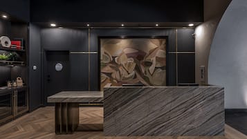 Una moderna zona de recepción con un mostrador de mármol, un cuadro abstracto de gran tamaño en la pared y suelo de madera oscura.