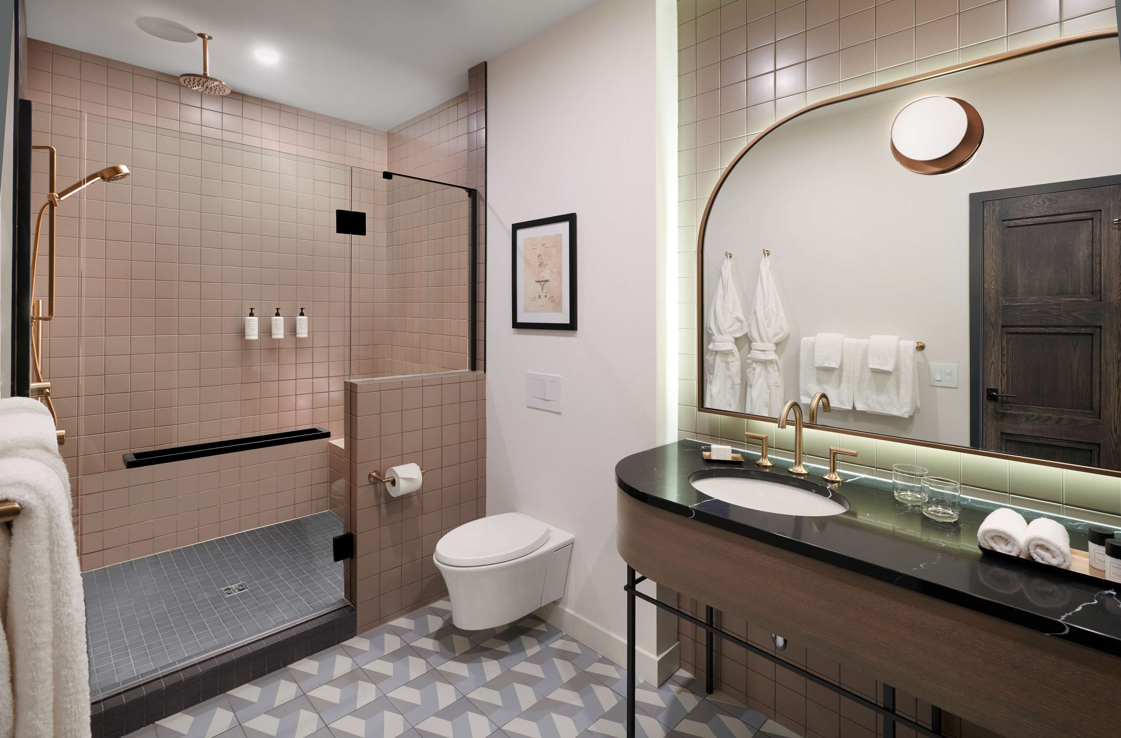 A modern bathroom with a shower, toilet, sink, and large mirror.