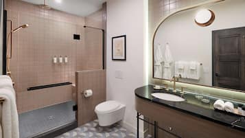 A modern bathroom with a shower, toilet, sink, and large mirror.