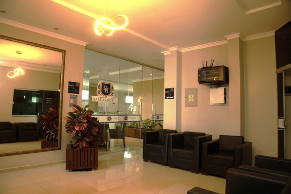 A hotel lobby with a reception desk, seating area, and a large mirror. - Dallas Hotel Premium (Altamira)