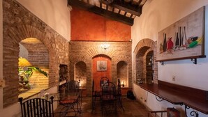 A rustic interior with stone arches, a wooden bar, and a painting on the wall. - El Beaterio (Santo Domingo)