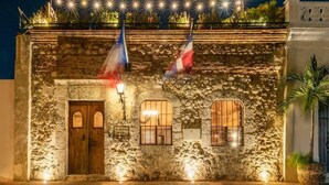 A stone building with a wooden door and two windows, illuminated by warm lighting. - El Beaterio (Santo Domingo)
