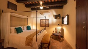 A bedroom with a four-poster bed, a bench, a chair, and a ceiling fan. - El Beaterio (Santo Domingo)