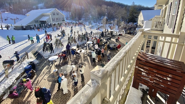 A ski resort with a large crowd, a building with a sign, and a clear sky.