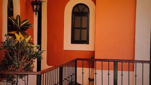 Ein Gebäude mit orangen Wänden, einem weißen Fenster und einem schwarzen Geländer.