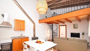 A kitchen with white cabinets, a white table, and a white chair. There is a staircase leading to an upper level. - Es Camp Pla 087 cosy finca with private pool, terrace, garden, barbecue and air-conditioning (Sineu)