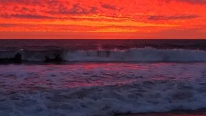 Un atardecer sobre el océano con olas rompiendo en la orilla.