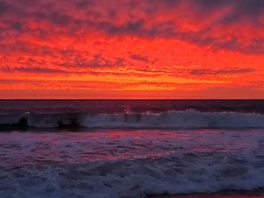 Tramonto sull'oceano con le onde che si infrangono sulla spiaggia.