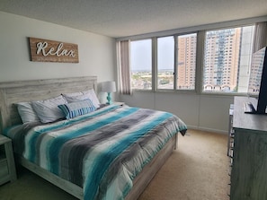 Una camera da letto con un letto grande, un comodino, una cassettiera e una finestra con vista sulla città.