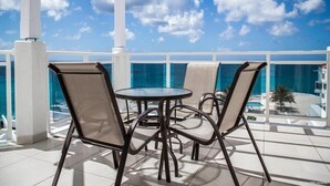 A covered outdoor seating area with a glass balustrade, a round table, and two chairs. - The Morgan Resort & Spa (Simpson Bay)