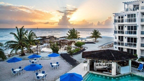 A resort with a pool, outdoor seating, and a view of the ocean at sunset. - The Morgan Resort & Spa (Simpson Bay)