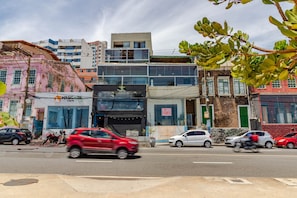 A street view with buildings, a red car, and a motorcycle.