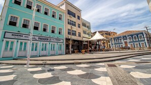 A street with buildings, including a restaurant named "BOHEMIA" and a bar named "PARADOR 21". - RV03 Quarto e Sala Vista Mar (Salvador)