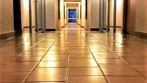 Um corredor comprido e estreito com chão de azulejos e paredes laterais.