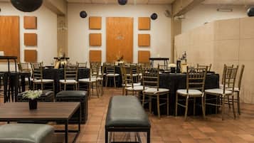Una sala de conferències amb diverses taules i cadires, parets de panells de fusta i un penjall.