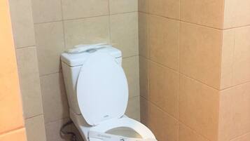 A standard white toilet in a bathroom with beige tiles on the walls and floor.