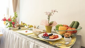 Un buffet della colazione con diversi tipi di frutta, verdura e un vaso di fiori.