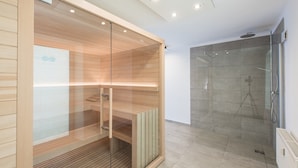 A modern bathroom with a glass-enclosed shower, wooden paneling, and a visible towel rack. - Superior Chalet with Sauna (Eisenerz)