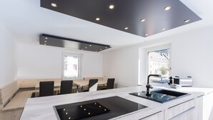 A modern kitchen with a built-in stove, a sink, and a dining area with wooden benches. - Superior Chalet with Sauna (Eisenerz)