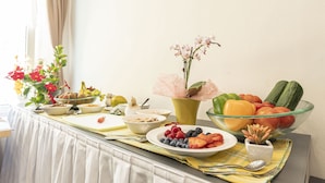 A breakfast buffet with various fruits, vegetables, and a vase of flowers. - Superior Chalet with Sauna (Eisenerz)