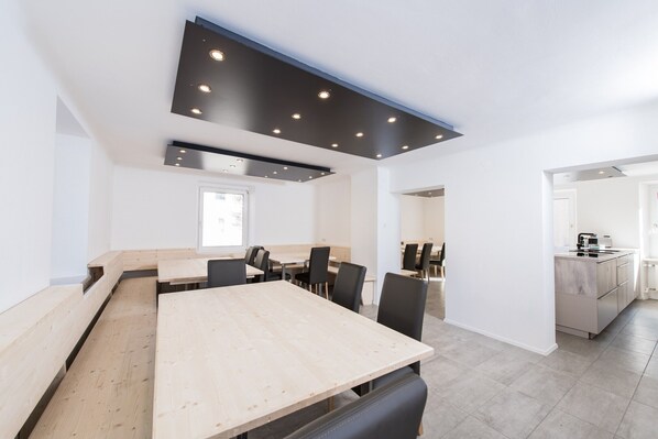 A modern kitchen with a central island, built-in appliances, and a dining area with a long table and chairs.