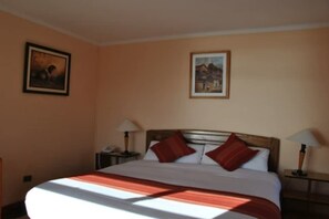 A hotel room with a large bed, two bedside tables with lamps, and two framed pictures on the walls. - Gloria Copacabana (Copacabana)