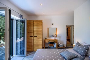 A bedroom with a bed, a desk, a chair, a wardrobe, and a large mirror.