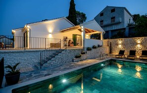 A modern villa with a swimming pool, stone steps, and outdoor seating.