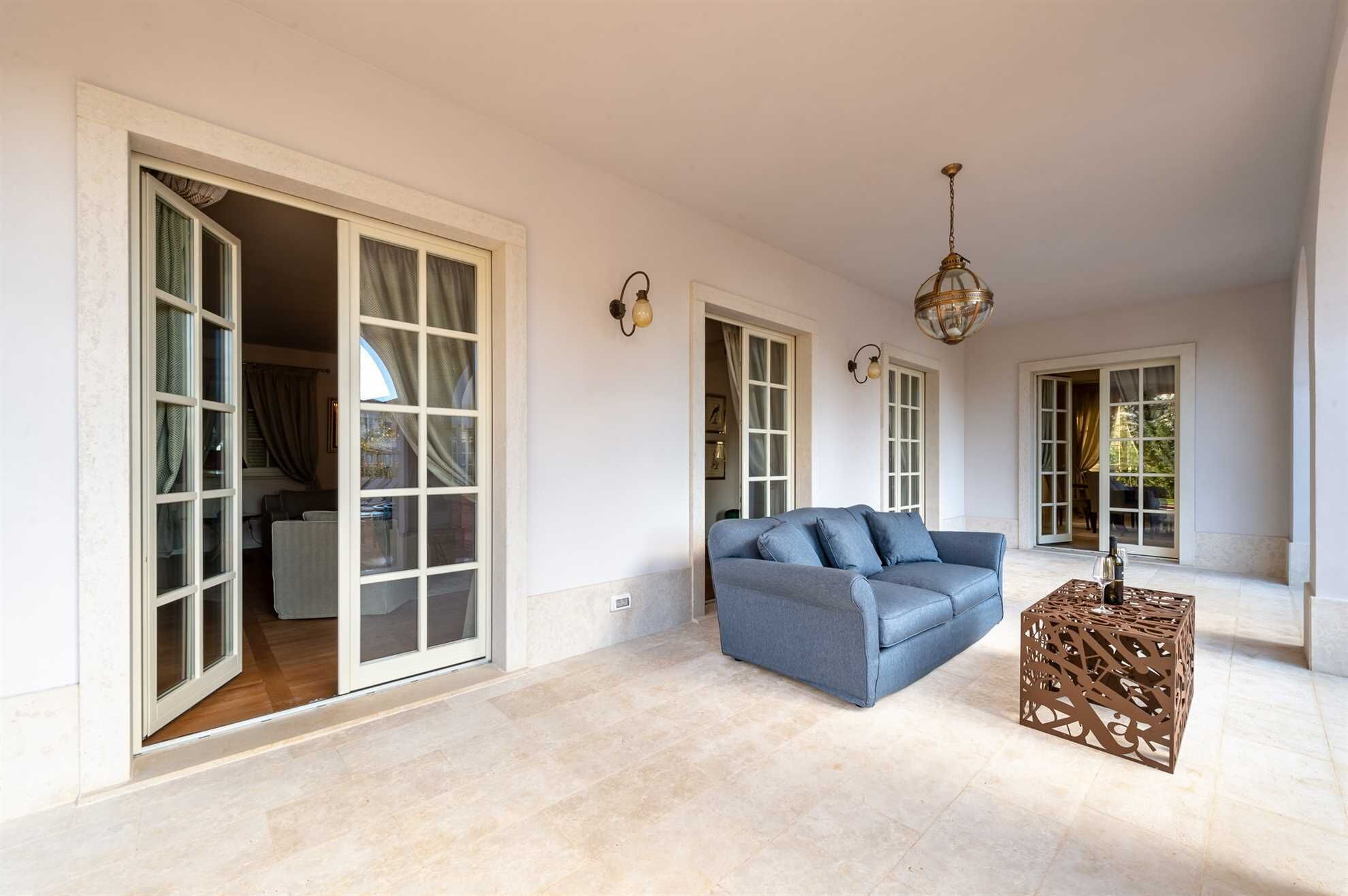 Un salon spacieux avec un canapé bleu, une table basse décorative en bois et de grandes portes-fenêtres coulissantes donnant sur un balcon.