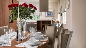 A dining table set for six with clear glassware and white plates, a vase with red roses, and a modern interior with a wooden cabinet and a painting on the wall. - Villa Palazzo di Zara with Pool (Vabriga)