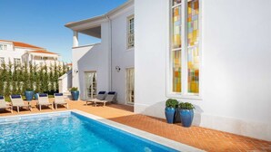 A swimming pool area with lounge chairs, a tiled deck, and a large window with stained glass. - Villa Palazzo di Giulia with Pool (Vabriga)