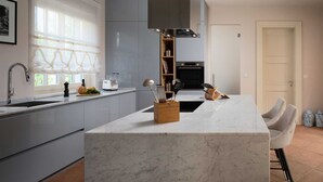 A modern kitchen with grey cabinets, a marble island, and a built-in oven. - Villa Palazzo di Giulia with Pool (Vabriga)