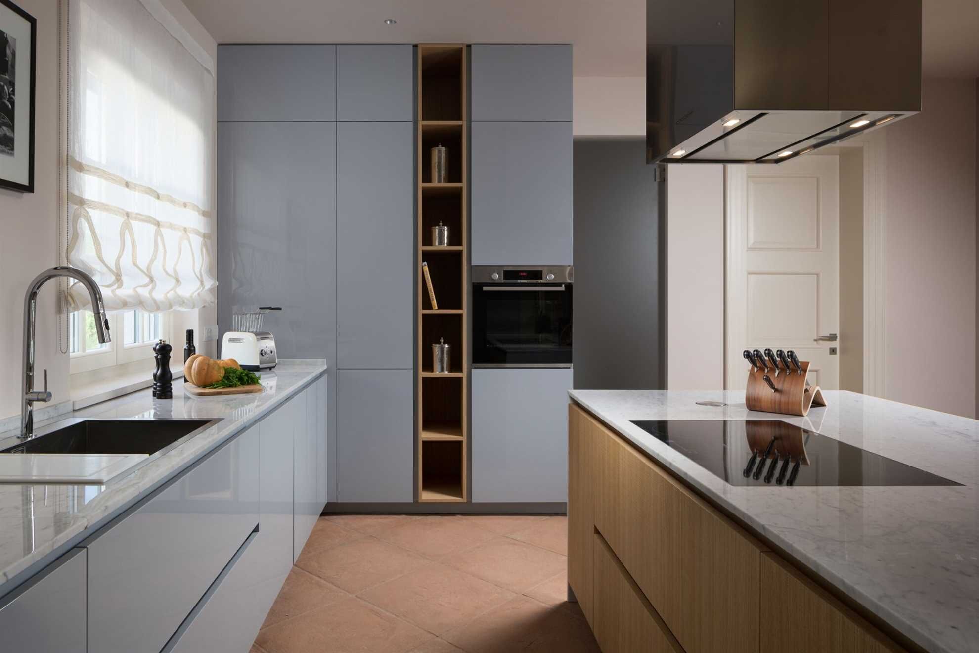 A modern kitchen with grey cabinets, a built-in oven, a sink, and a knife block.