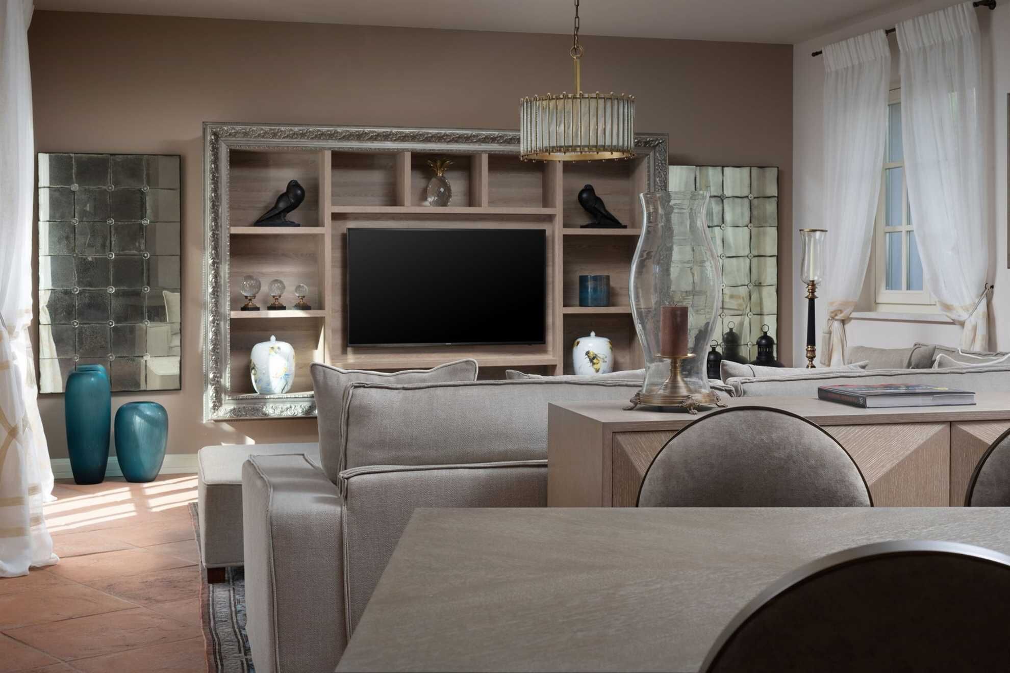 Ein modernes Wohnzimmer mit einem großen Flachbildfernseher, bequemen Sitzmöglichkeiten und Dekorationselementen.