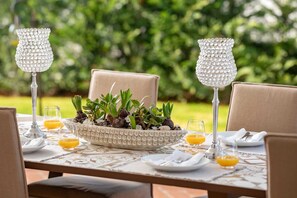 A table set for two with a decorative bowl of plants, two crystal candle holders, and glasses of orange juice.