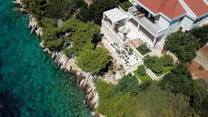 A modern two-story building with a balcony and a garden area. - Beachfront Villa Sea Touch (Okrug Donji)