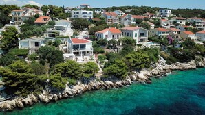 A coastal residential area with houses built on rocky terrain, overlooking clear turquoise waters. - Beachfront Villa Sea Touch (Okrug Donji)