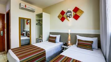 A hotel room with two beds, a mirror, a wardrobe, and a wall-mounted air conditioner.