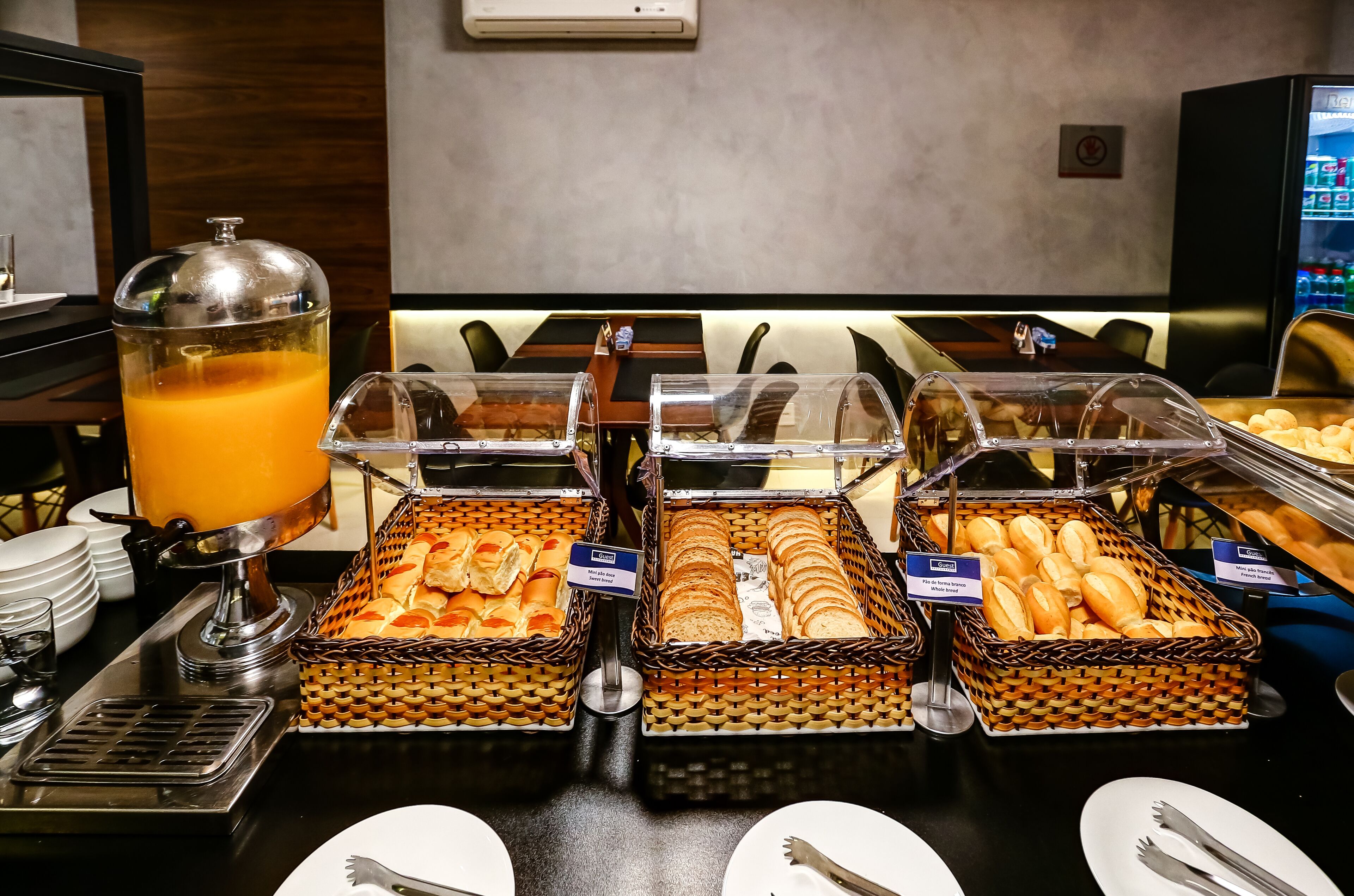 A buffet with various food items including orange juice, bread, and pastries.